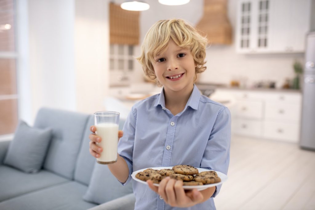 Boy holding glass of milk and biscuits